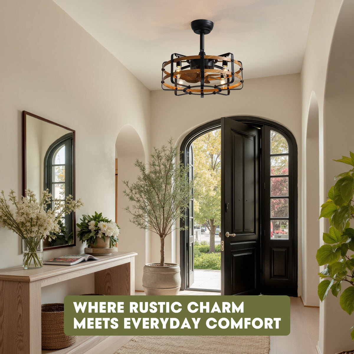 Farmhouse caged ceiling fan in foyer — arched black door, console table with mirror and flowers, olive tree, "Where Rustic Charm Meets Everyday Comfort" text, bright entryway | CARRA HOME