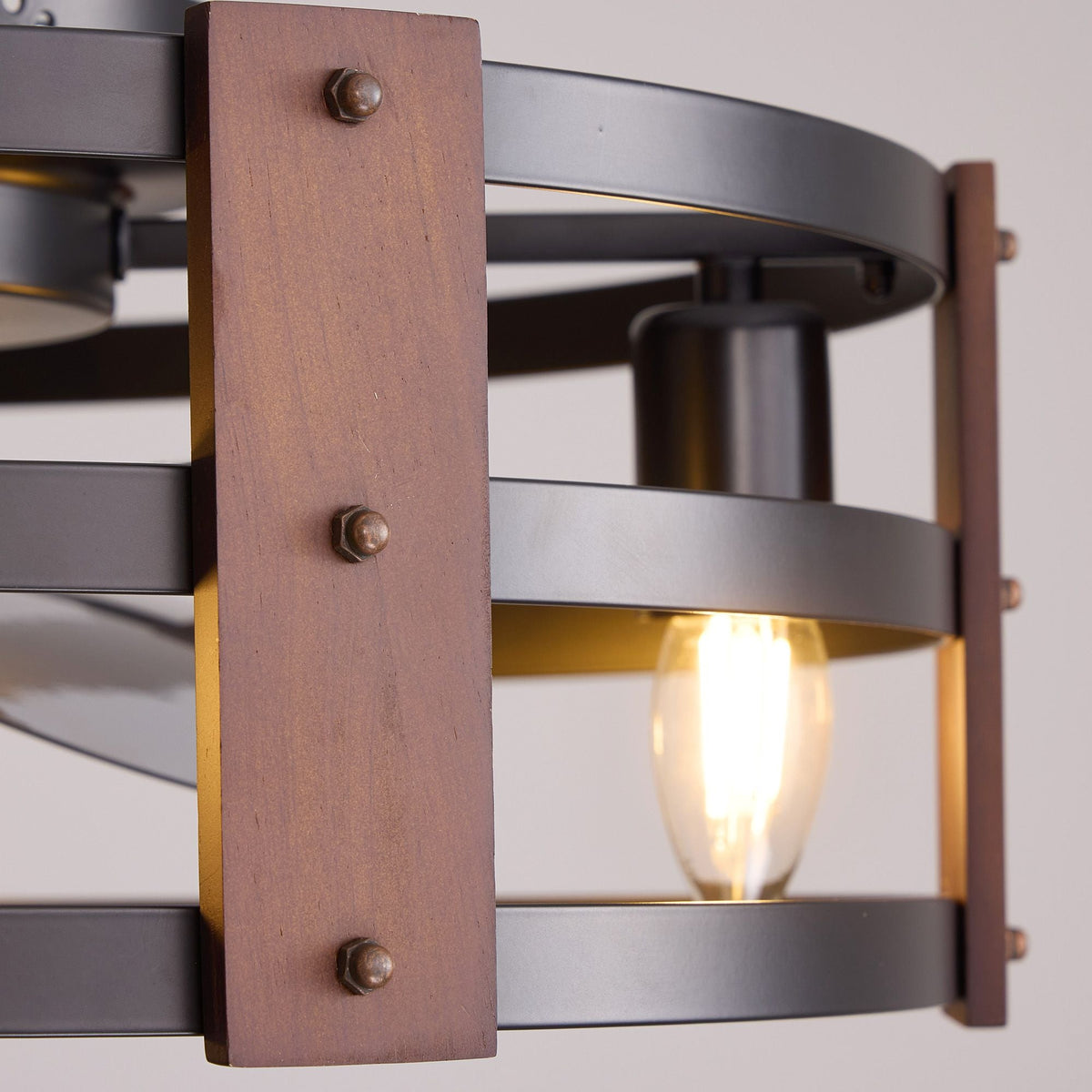 Close-up of rustic wood panel with metal rivets and vintage Edison bulb — matte black cage, warm glow, industrial farmhouse craftsmanship detail | CARRA HOME