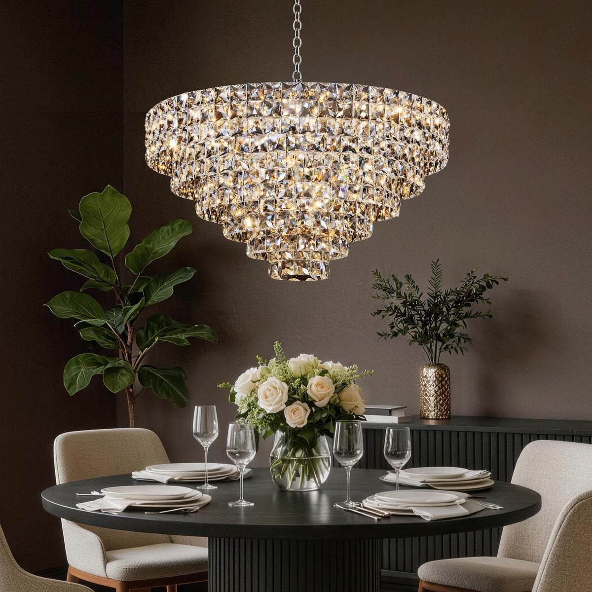 Aria Modern Gold K9 Crystal Glacier Chandelier in a sophisticated dining room — glowing warmly above a round wooden table, velvet chairs, and white floral centerpiece for elegant dinner parties | Carra Home