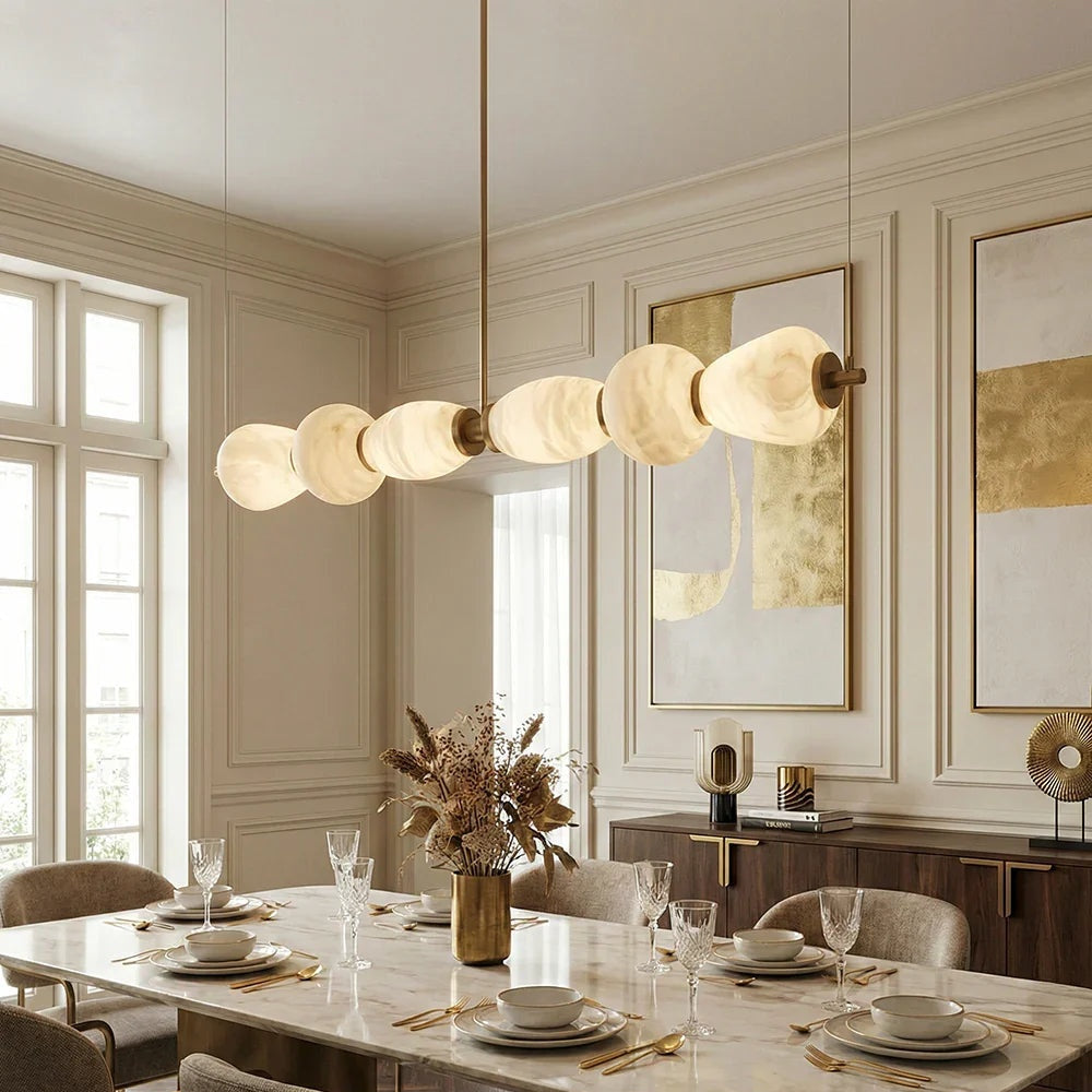 Alabaster pebble chandelier in a dining room beside tall windows | CARRA HOME