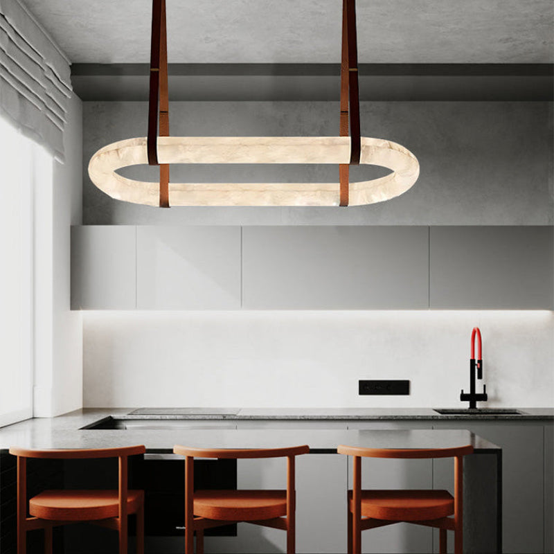 Gold leather oval alabaster chandelier above an island with dark cabinetry | CARRA HOME