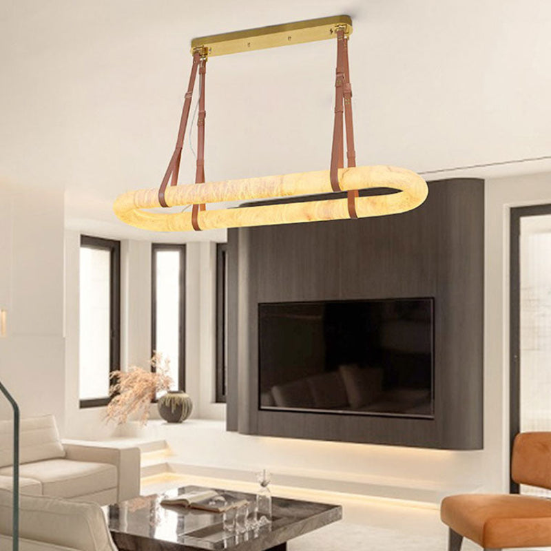 Gold leather oval alabaster chandelier in an open living and dining room | CARRA HOME
