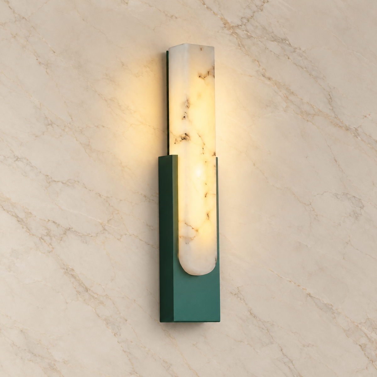 Emilia Alabaster Wall Sconce with green metalwork, illuminated on a marble wall | CARRA HOME