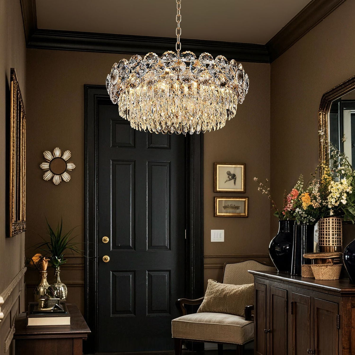 Glacia Modern Luxury Staggered K9 Crystal Flush Mount Chandelier in a foyer — hanging above a black double door with gold accents, next to a console table with flowers and candles | Carra Home