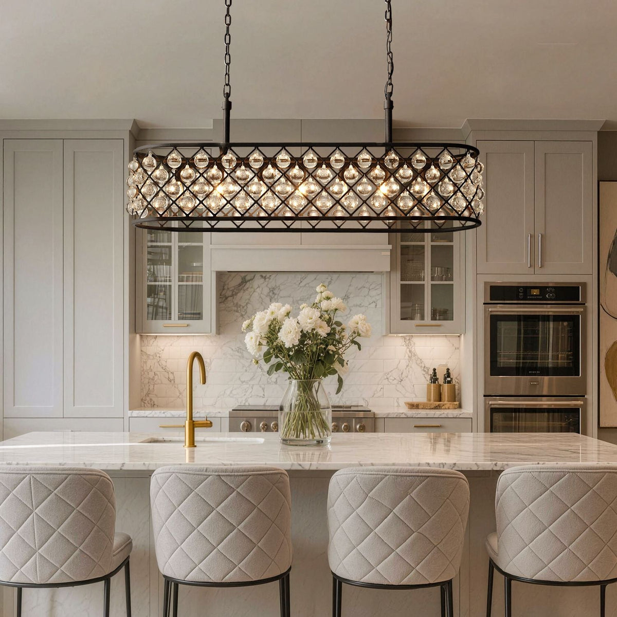 Harlow Modern Industrial Matte Black K9 Crystal Rectangle Chandelier in a kitchen island — hanging above a marble countertop with bar stools, a vase of white flowers, and modern kitchen appliances | Carra Home
