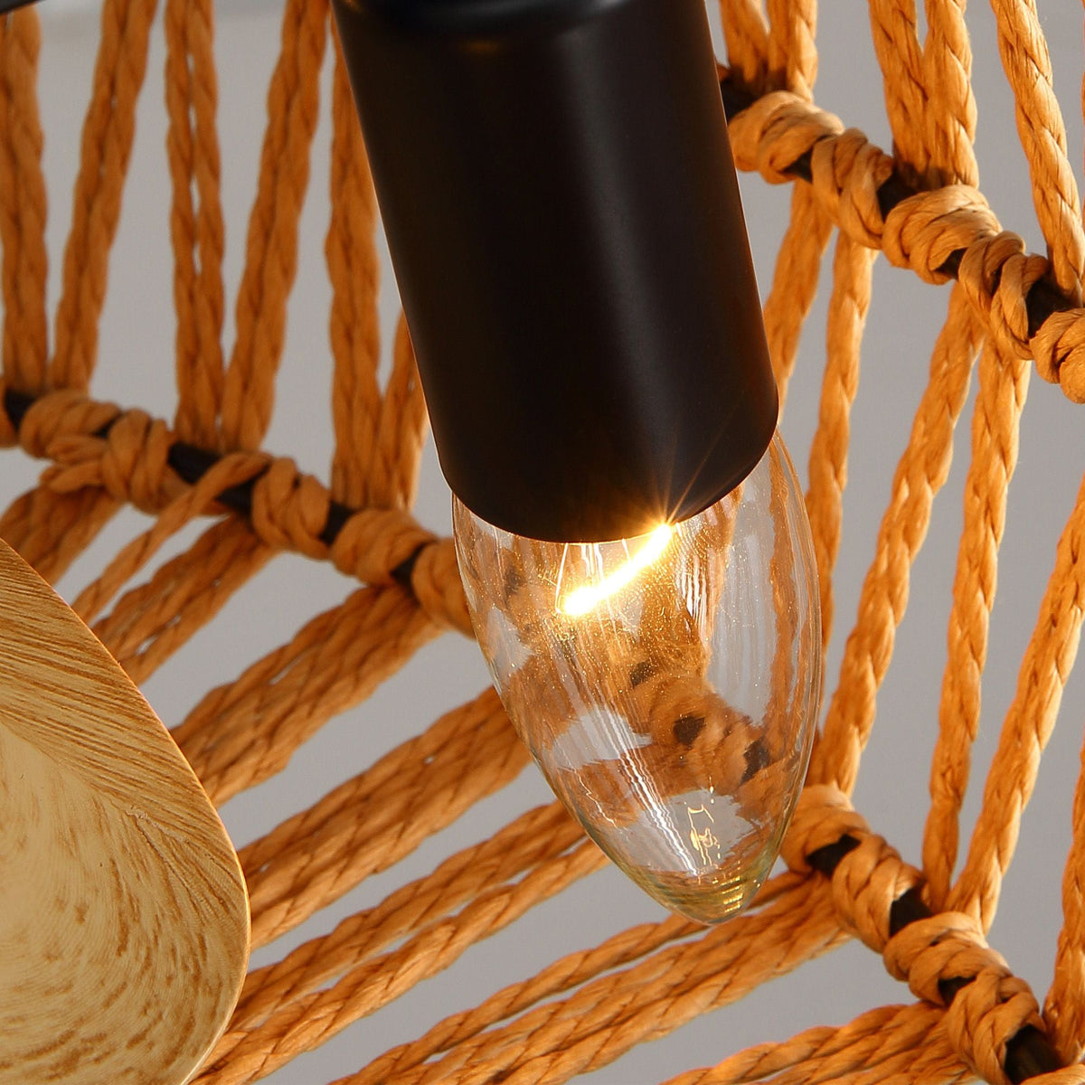 Haven Ceiling Fan light bulb detail — matte black socket, warm filament glow through woven shade, rustic modern accent | CARRA HOME