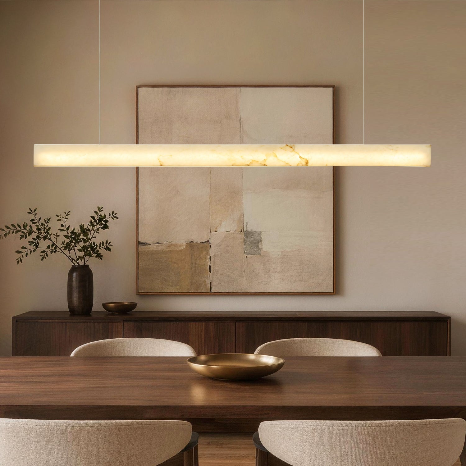 Horizon Modern Minimalist Alabaster Ultra-Slim Linear LED Chandelier in a dining room — suspended above a wooden dining table with a black bowl centerpiece, dark wood cabinet, and abstract wall art in the background -carra-home