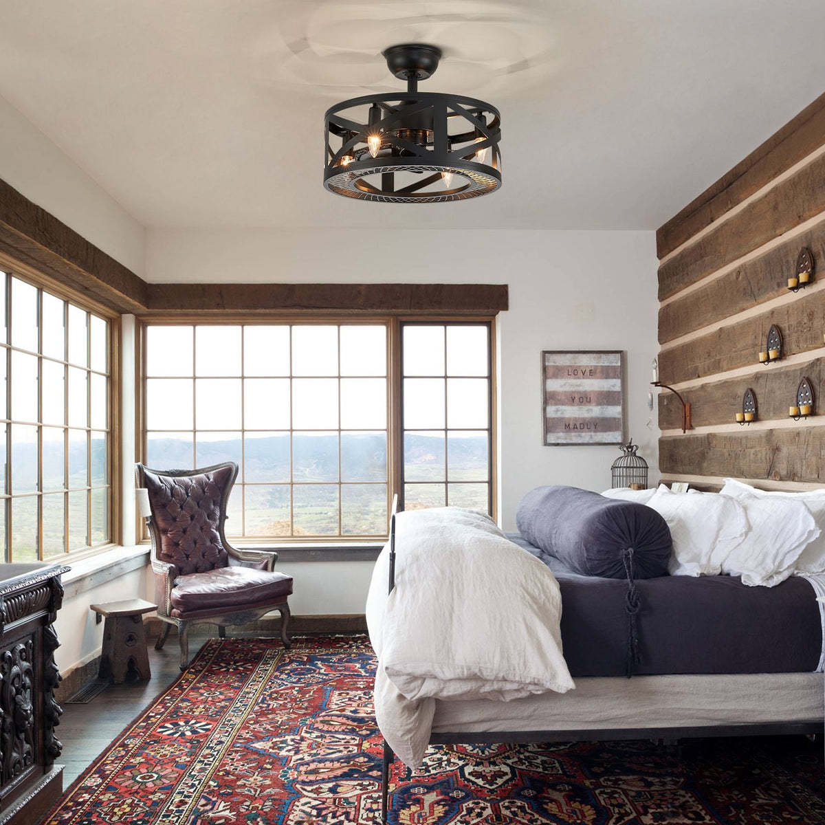 Industrial ceiling fan in rustic bedroom — wood plank walls, large windows with view, patterned rug, vintage farmhouse decor | CARRA HOME