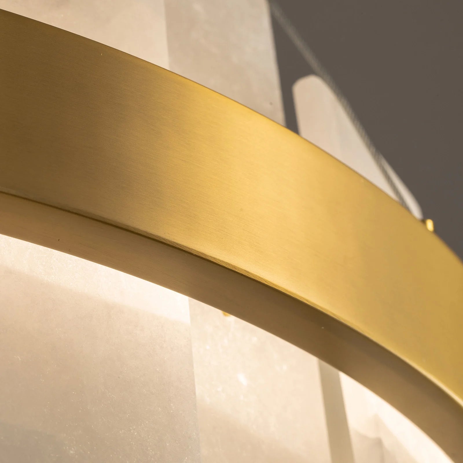 close-up-of-modern-round-alabaster-gold-chandelier-with-circular-gold-frame-and-evenly-spaced-alabaster-panels-emitting-warm-light-carra-home
