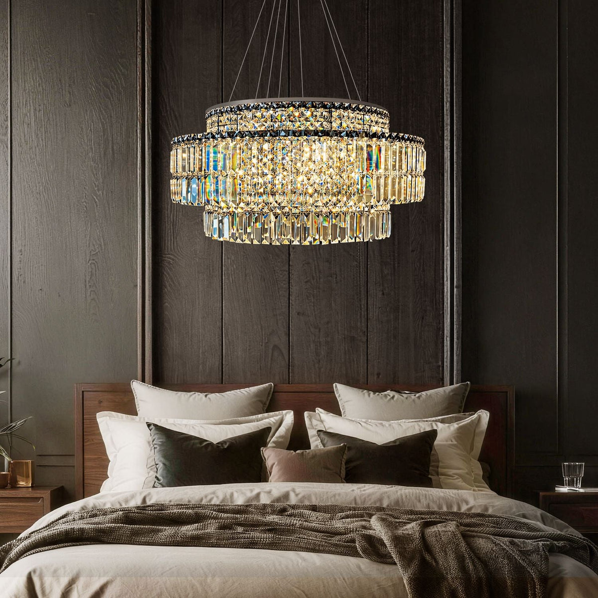 Stellar Modern Silver Multi-Faceted K9 Crystal Round Chandelier in a bedroom — hanging above a wooden bed with layered bedding, nightstands, and dark wood paneling | Carra Home