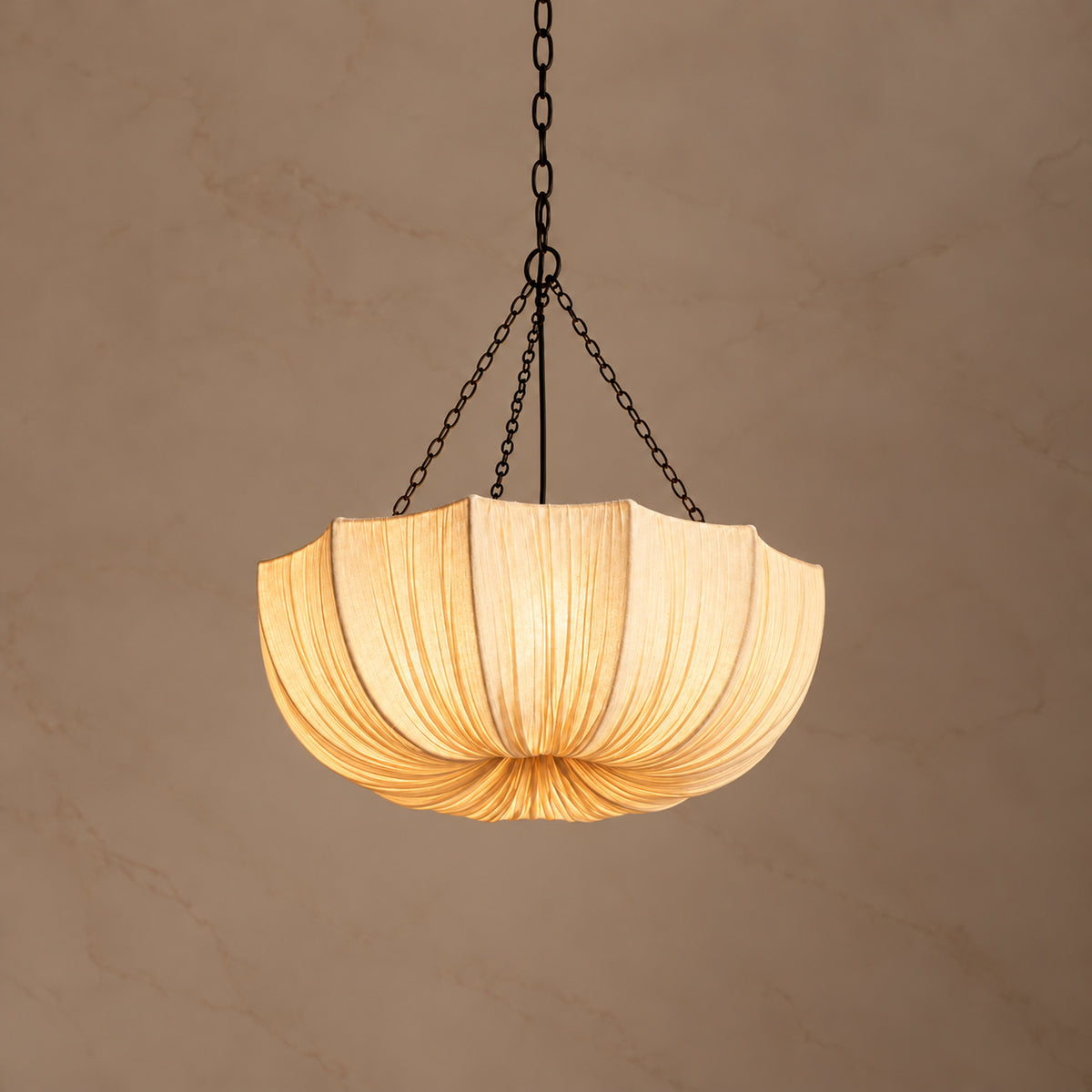 Aldwin 60 cm cotton pleated dome pendant light switched on against a warm neutral background | CARRA HOME