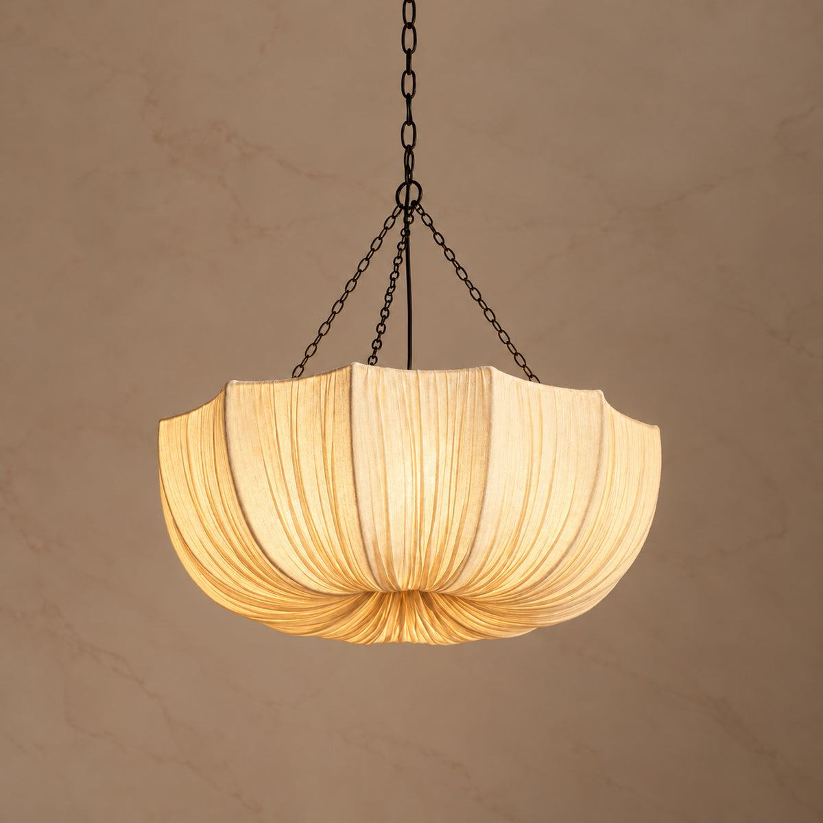 Aldwin 80 cm cotton pleated dome pendant light switched on against a warm neutral background | CARRA HOME