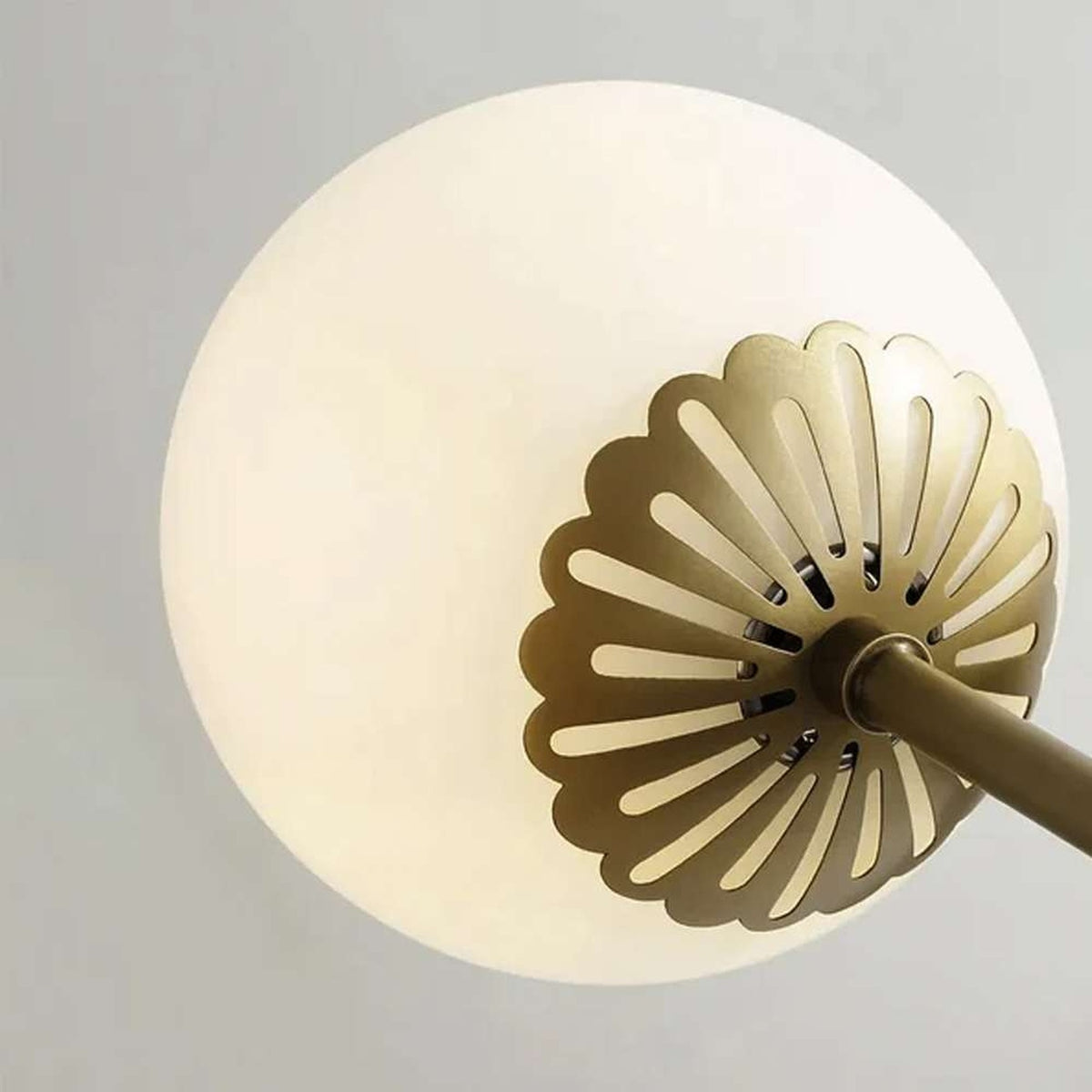 Close-up of the Dewdrop chandelier's perforated brass floral cap and opal glass globe | CARRA HOME