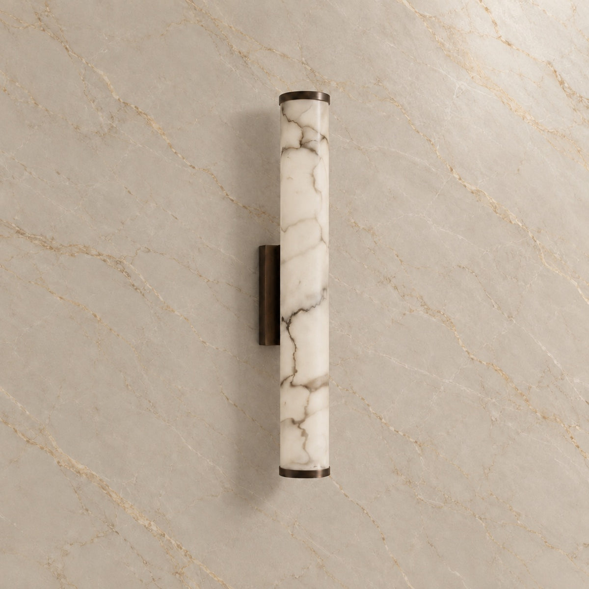 Falynis Alabaster Cylinder Wall Sconce with black hardware, switched off, on a marble wall | CARRA HOME
