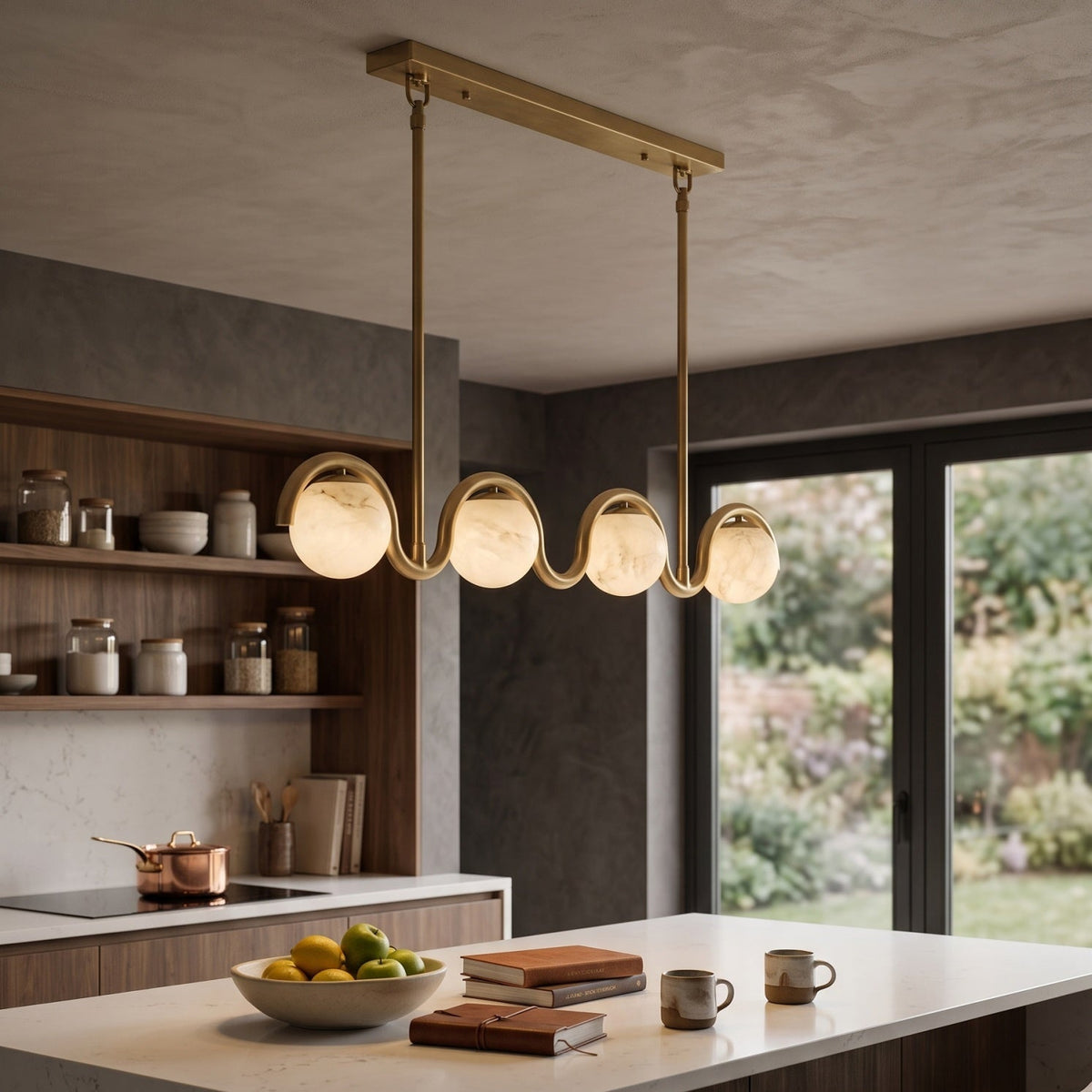 Gold wave chandelier above a stone kitchen island | CARRA HOME