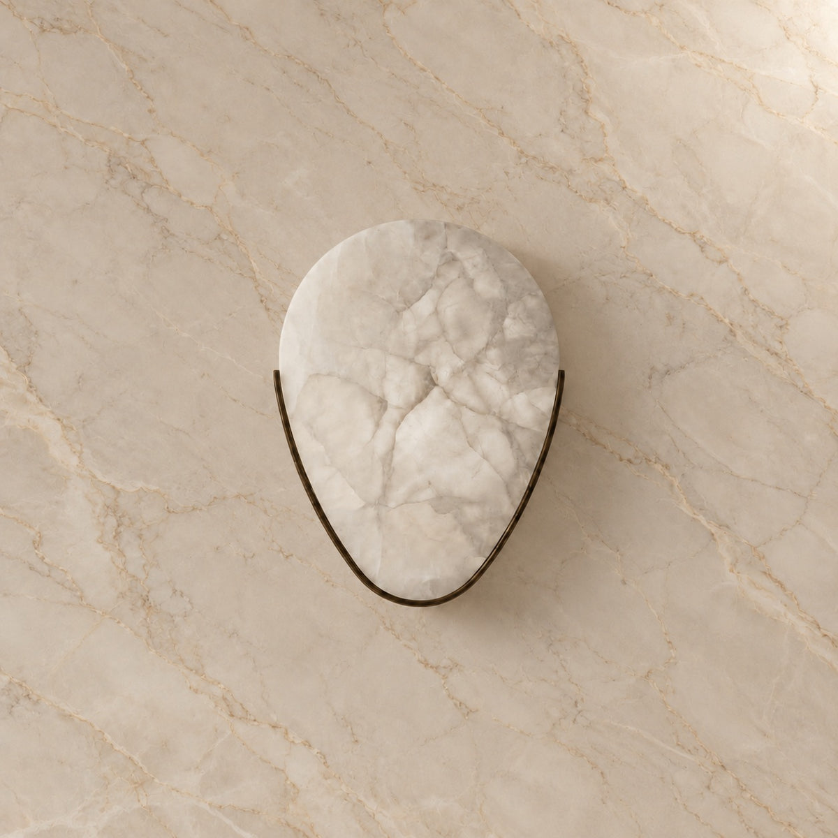 Ritu Alabaster Teardrop Wall Sconce with bronze hardware, switched off, on a marble wall | CARRA HOME