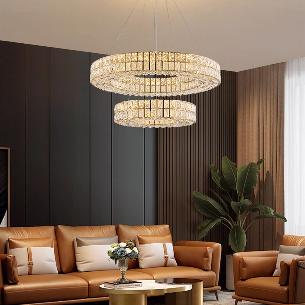 Selene Crystal Double-Ring Chandelier in a modern living room — dark paneled walls, beige sofa, abstract art, and cozy ambient lighting from above | Carra Home