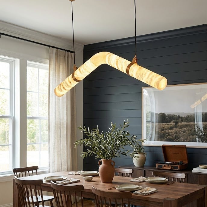 Curved alabaster tube chandelier above a wood dining table | CARRA HOME