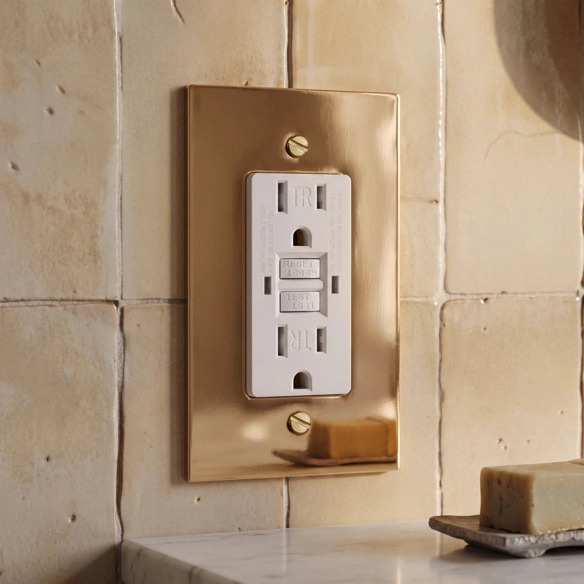 The Polished Brass Outlet — White GFCI polished brass outlet on a stone wall | CARRA HOME
